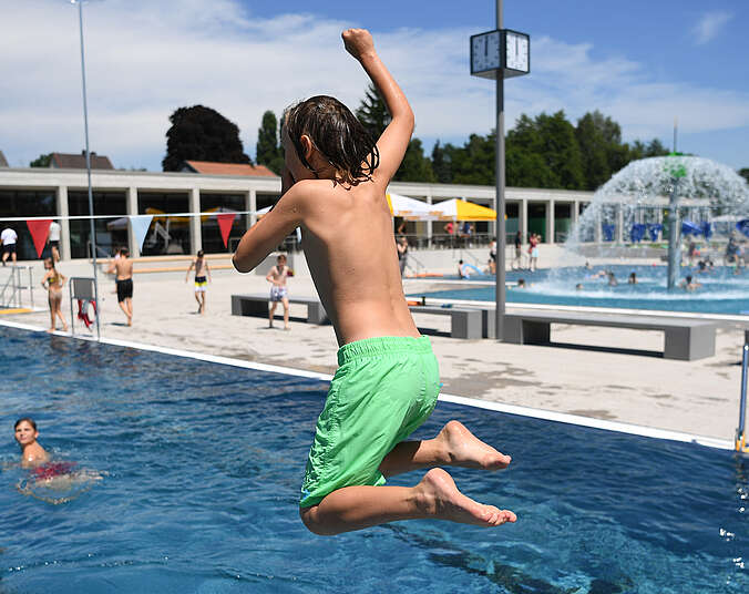 Junge in grüner Badehose springt ins Wasser im Frei- und Seebad Fischbach