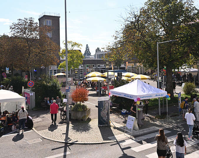 Blick auf eine Platz mit Sonnenschirmen und Menschen.