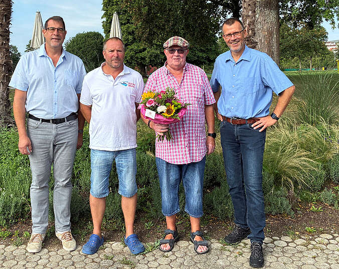 Eine Gruppe von vier Männern, einen trägt einen Blumenstrauß.