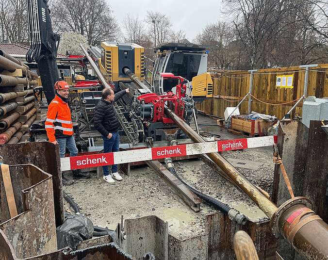 2 Männer auf einer Baustelle, rechts ist eine Bohrgestänge sichtbar