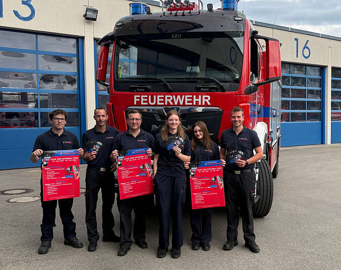 Männer und Frauen in Feuerwehr-Uniform stehen vor einem Feuerwehrfahrzeug.