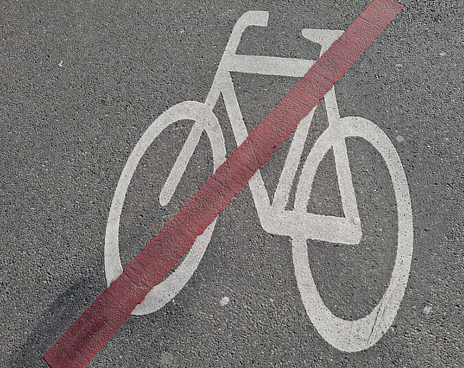 weißes Fahrrad mit roten Balken durchgestrichen auf Asphalt