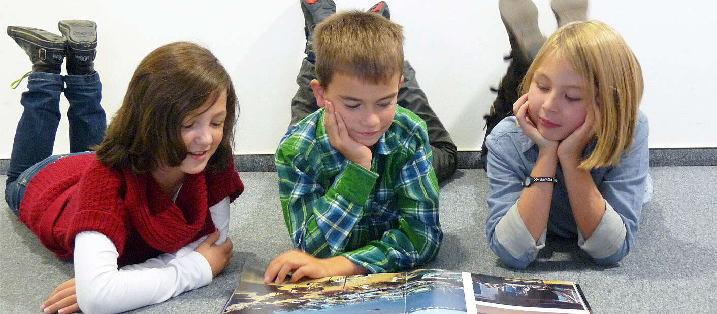 Drei Kinder lesen ein Buch