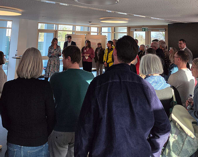 Frauen und Männer stehen im Halbkreis